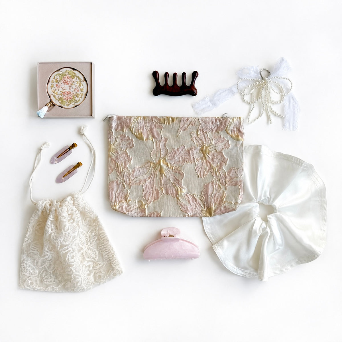 Rose Gold Lace gift set flat-lay including a jacquard pouch, lace drawstring bag, satin scrunchie, wooden hair comb, pearl bow keychain, mother-of-pearl claw clip, pink claw clip, and round hand mirror
